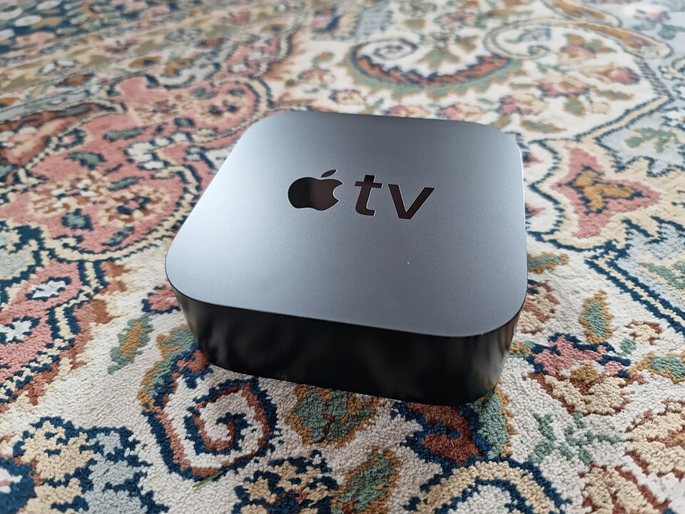 Fjärrkontroll i handen framför en tv-skärm med kanaler i iptv extreme