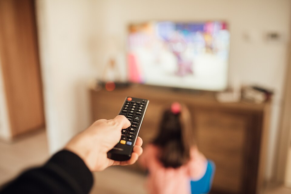 Barn och förälder tittar på tv tillsammans med en iptv-spelare igång i bakgrunden
